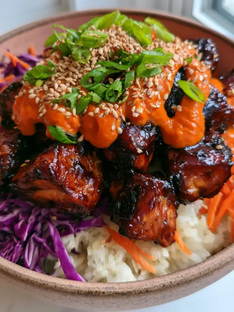 Bowl de cerámica rústica con pollo bbq coreano, vegetales coloridos y arroz humeante.