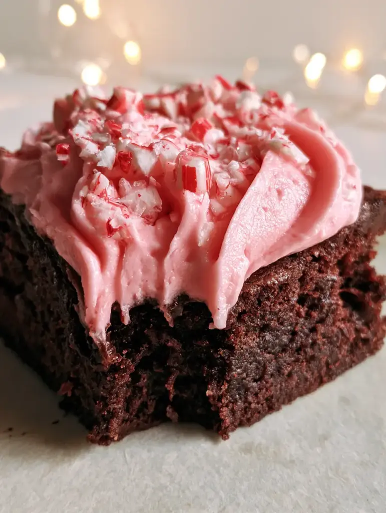 Brownies Navideños: La Receta Definitiva con Frosting de Menta y Bastones de Caramelo 1 Detalle del frosting de menta brillante y los pedazos de bastón de caramelo rojos y blancos sobre brownie.